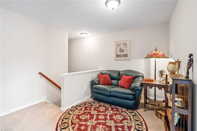 living area featuring carpet, baseboards, and an upstairs landing