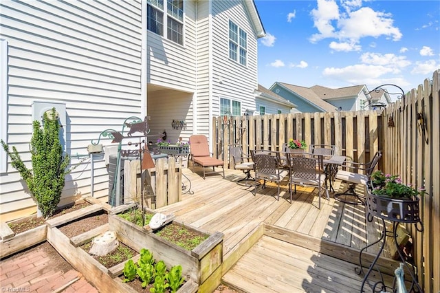 wooden deck featuring outdoor dining area, a garden, and fence