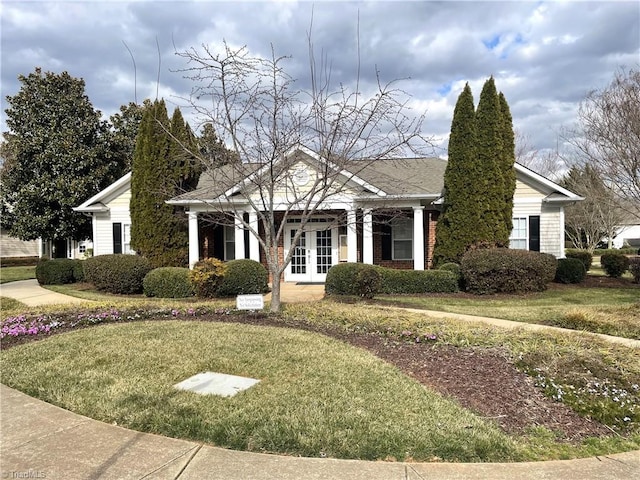 view of front of house with brick siding, a front yard, and french doors