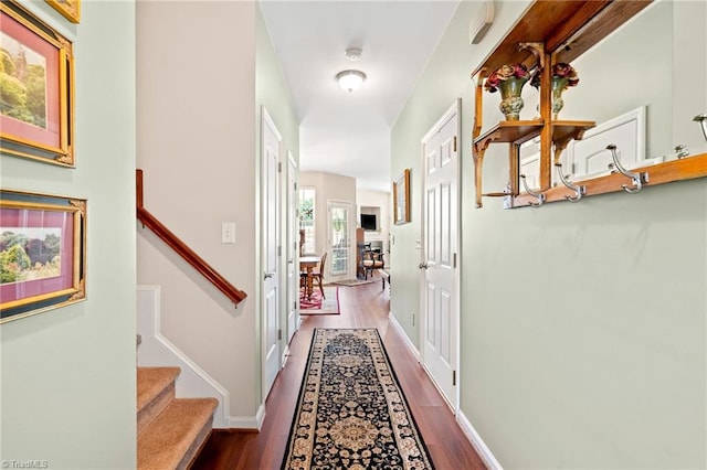 corridor featuring baseboards, stairway, and wood finished floors