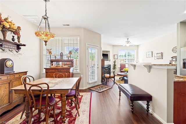 dining space with baseboards, visible vents, a ceiling fan, dark wood-style floors, and a fireplace