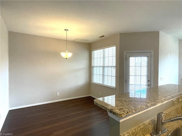 kitchen with light stone counters, dark wood-style flooring, visible vents, and baseboards