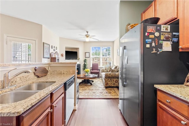 kitchen with light stone counters, stainless steel appliances, open floor plan, a sink, and ceiling fan