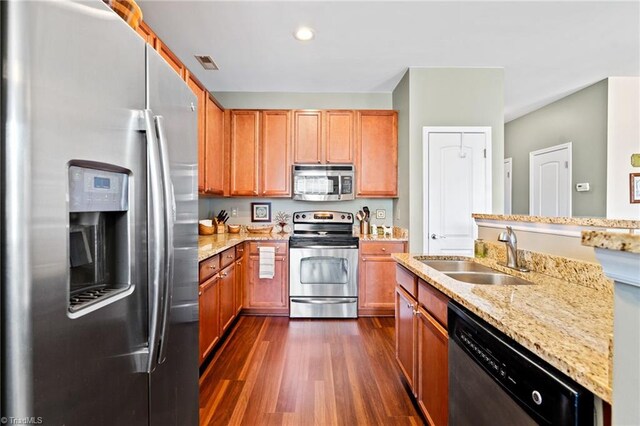 kitchen featuring visible vents, dark wood-style floors, appliances with stainless steel finishes, light stone counters, and a sink