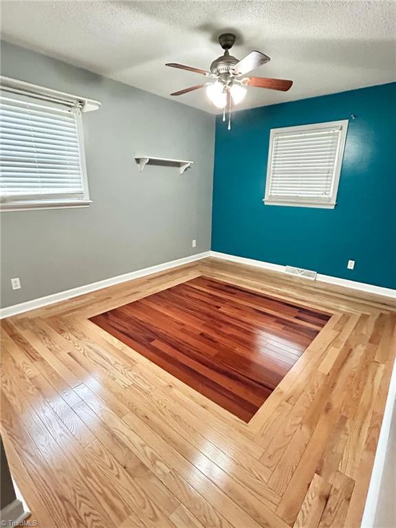 empty room featuring hardwood / wood-style floors, ceiling fan, and a textured ceiling