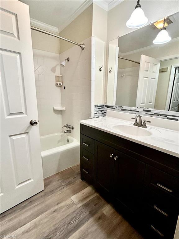 full bathroom featuring vanity, shower / tub combination, wood finished floors, and ornamental molding