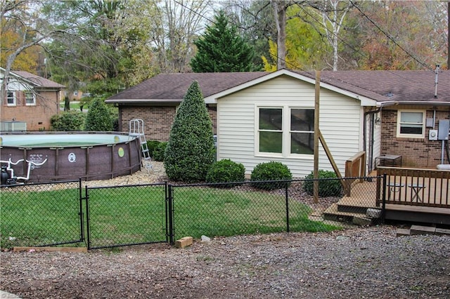 view of front of property with a front lawn, a gate, fence, a fenced in pool, and brick siding