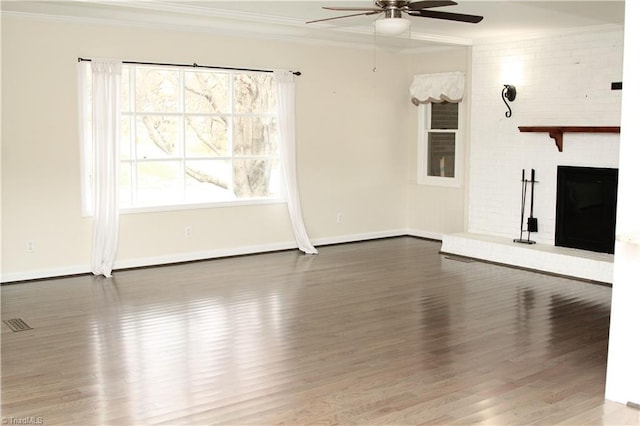 unfurnished living room with a brick fireplace, ceiling fan, crown molding, and wood-type flooring