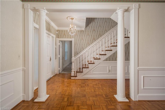 foyer featuring ornamental molding, an inviting chandelier, and parquet floors