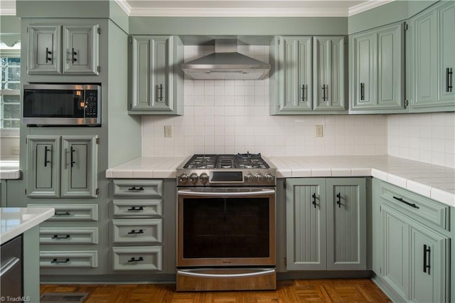 kitchen featuring appliances with stainless steel finishes, wall chimney exhaust hood, ornamental molding, and backsplash