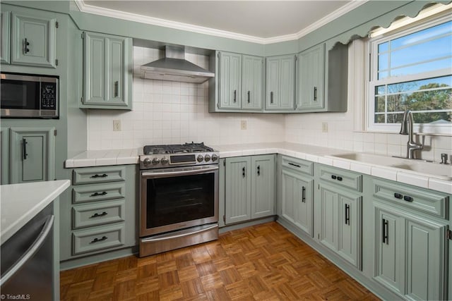 kitchen featuring appliances with stainless steel finishes, wall chimney exhaust hood, sink, and backsplash