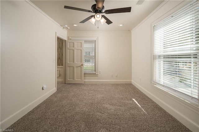 carpeted spare room featuring ornamental molding, ceiling fan, and plenty of natural light