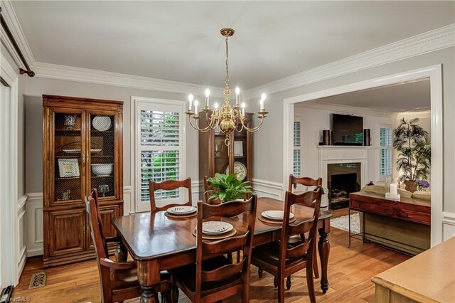 226 Cedar Trl, Winston-Salem, NC 27104 - dining area featuring light wood finished floors, a chandelier, ornamental molding, a fireplace, and wainscoting