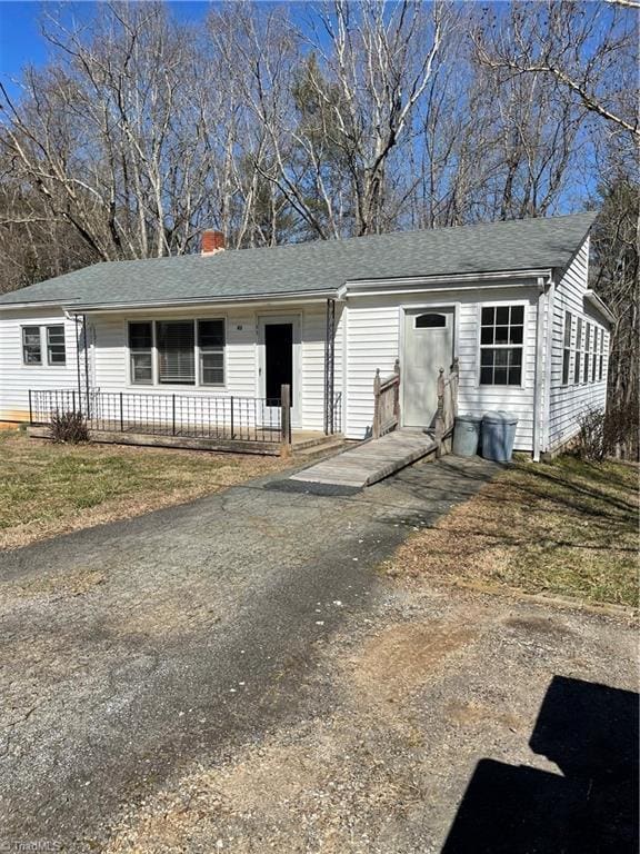 single story home with entry steps, roof with shingles, and a chimney