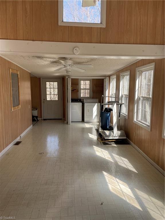 interior space featuring separate washer and dryer, a wealth of natural light, and wooden walls