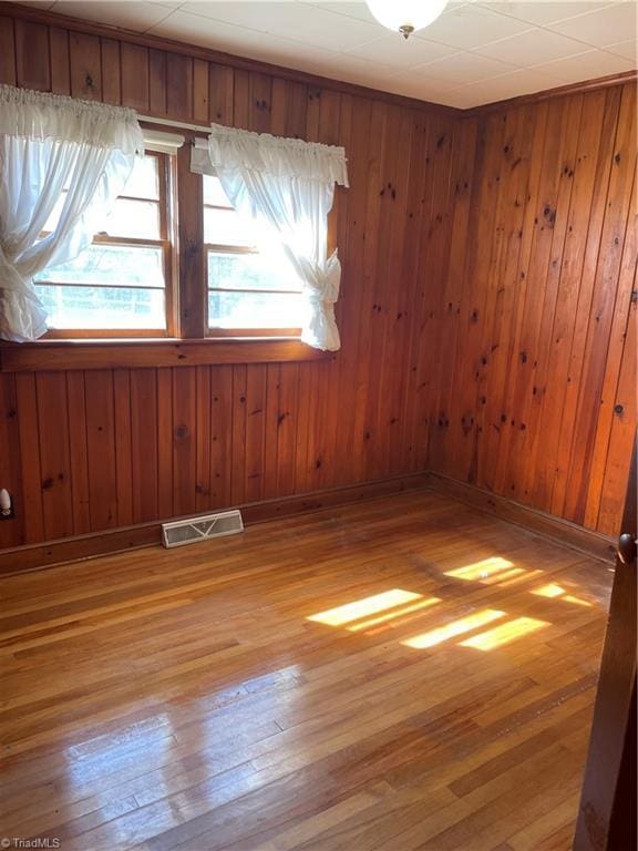 spare room featuring light wood-type flooring, visible vents, and baseboards