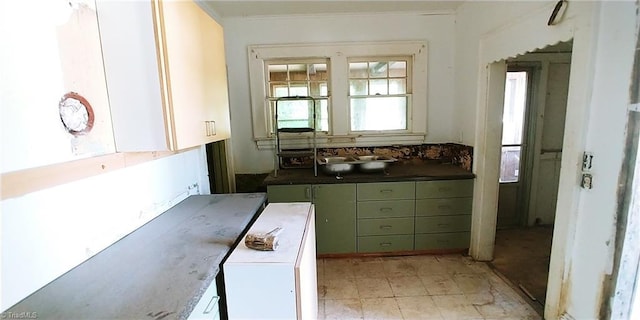 kitchen with a sink, dark countertops, and green cabinets