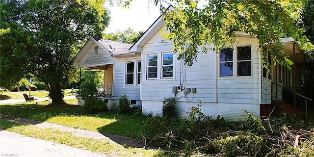 view of side of property with crawl space and a lawn