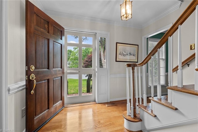 entrance foyer with stairway, crown molding, light wood finished floors, and a notable chandelier