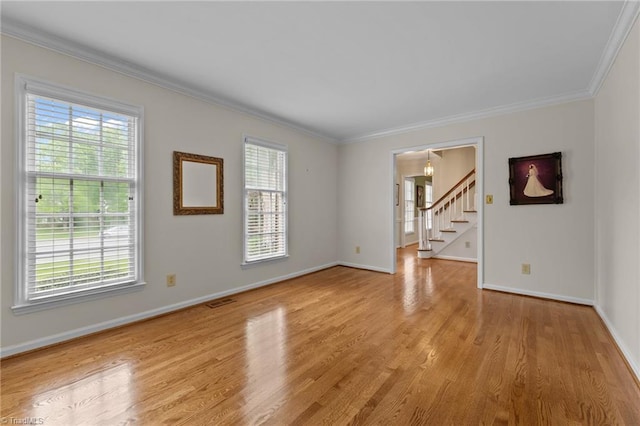 spare room featuring crown molding, plenty of natural light, stairway, and light wood-style flooring
