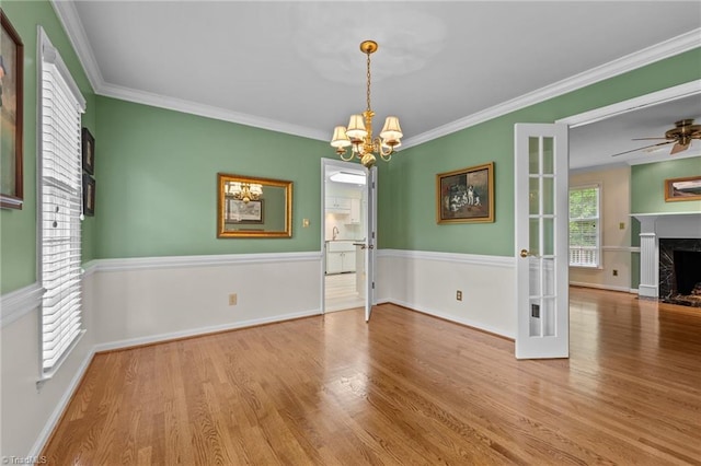 unfurnished dining area with baseboards, a high end fireplace, wood finished floors, and ornamental molding