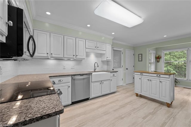 kitchen featuring backsplash, appliances with stainless steel finishes, a sink, white cabinets, and ornamental molding