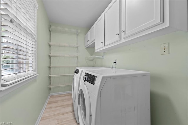 laundry area featuring baseboards, light wood-type flooring, cabinet space, and washer and dryer