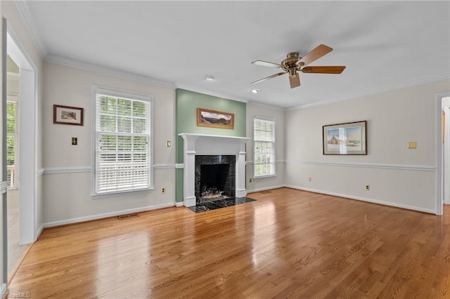 unfurnished living room with a high end fireplace, ornamental molding, and a wealth of natural light