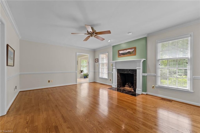 unfurnished living room with visible vents, wood finished floors, baseboards, a ceiling fan, and a wealth of natural light