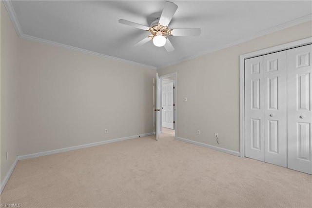 unfurnished bedroom with a ceiling fan, baseboards, a closet, ornamental molding, and light carpet