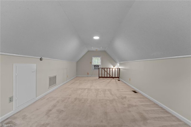 additional living space with carpet floors, baseboards, lofted ceiling, and visible vents