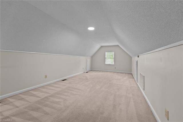 additional living space featuring carpet floors, visible vents, lofted ceiling, baseboards, and a textured ceiling