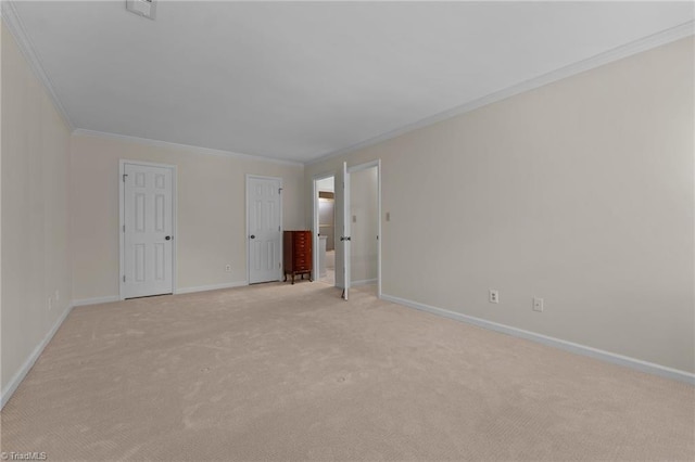 empty room with baseboards, ornamental molding, and light carpet