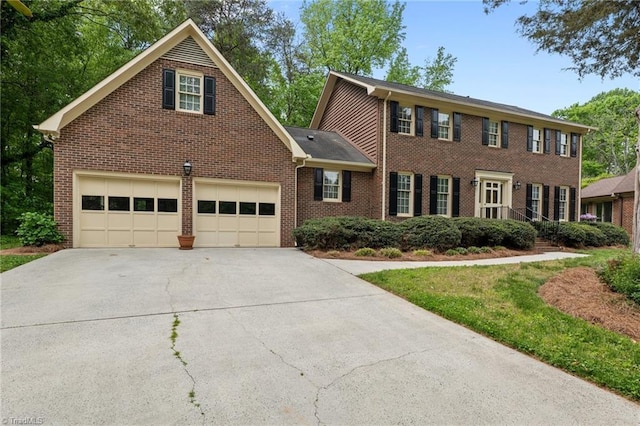 colonial house with a garage, driveway, and brick siding