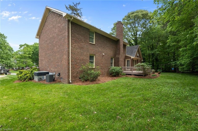 back of property featuring a yard, brick siding, central AC, and a chimney