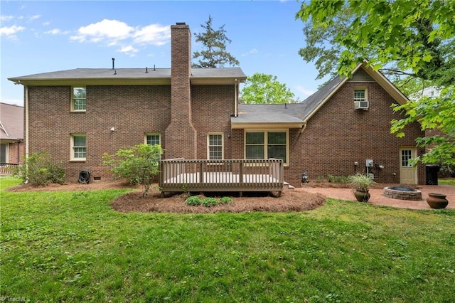 rear view of property with a lawn, a fire pit, a wooden deck, and a chimney