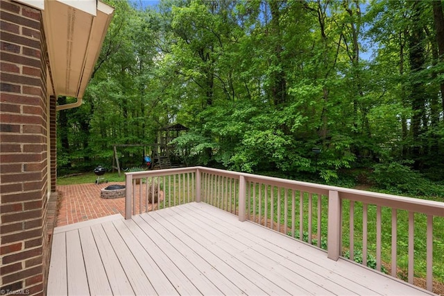 wooden terrace featuring a playground and an outdoor fire pit