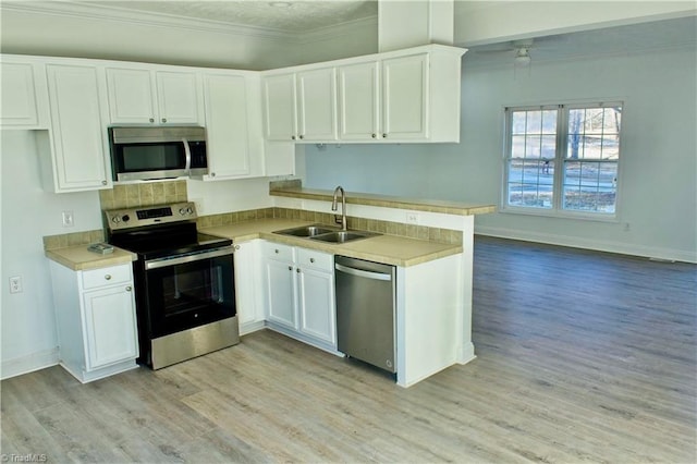 kitchen featuring white cabinets, sink, ornamental molding, light hardwood / wood-style floors, and stainless steel appliances