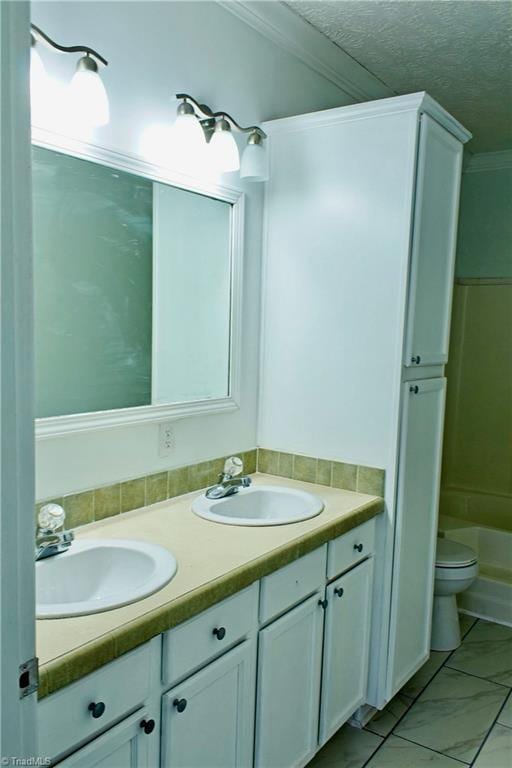 full bathroom featuring toilet, vanity, a textured ceiling, and ornamental molding