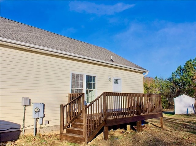 back of property featuring a storage shed and a wooden deck