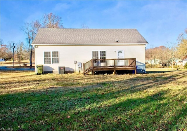 rear view of property featuring a deck, a yard, and central AC