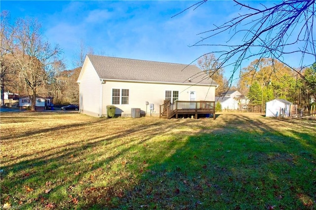 back of property with a lawn, a wooden deck, and a shed