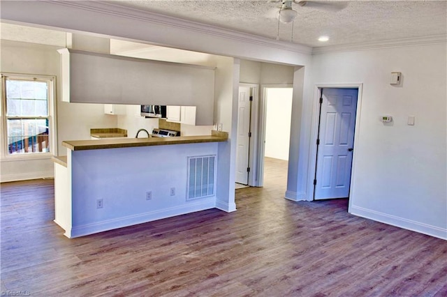 kitchen with kitchen peninsula, white cabinets, wood-type flooring, and a textured ceiling