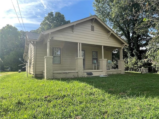 bungalow-style home featuring covered porch and a front yard