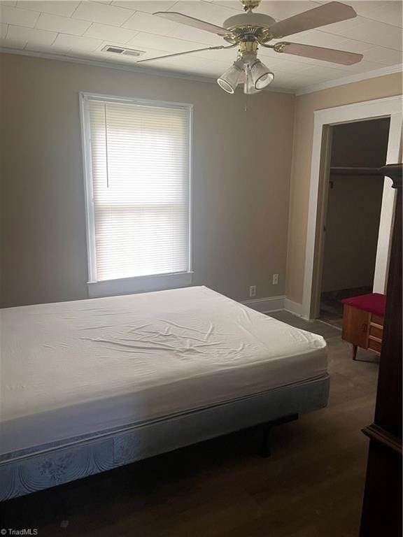 unfurnished bedroom featuring ornamental molding, hardwood / wood-style flooring, ceiling fan, and a closet