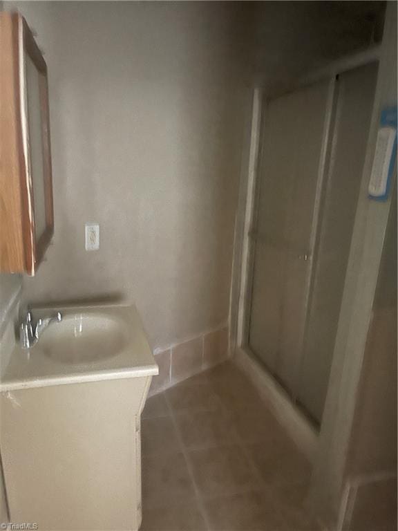 bathroom with tile patterned floors, a shower with door, and vanity