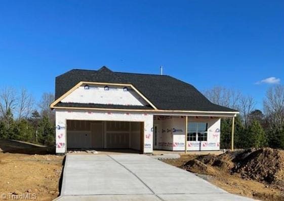 property in mid-construction featuring concrete driveway, an attached garage, and covered porch