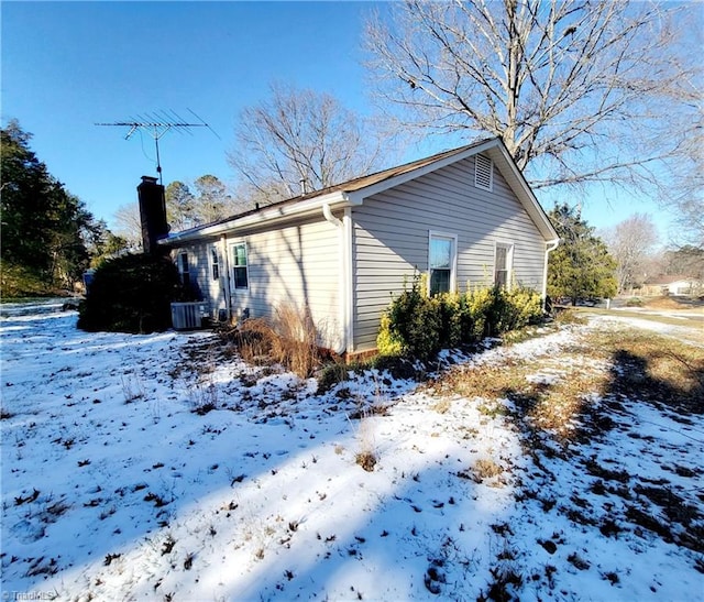 snow covered property with central AC unit