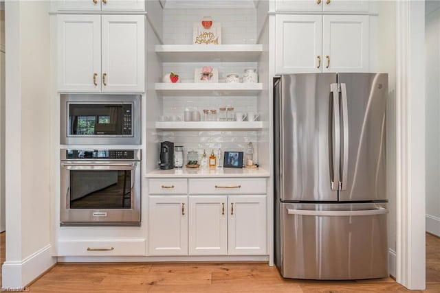 kitchen with open shelves, light countertops, white cabinets, appliances with stainless steel finishes, and light wood-type flooring