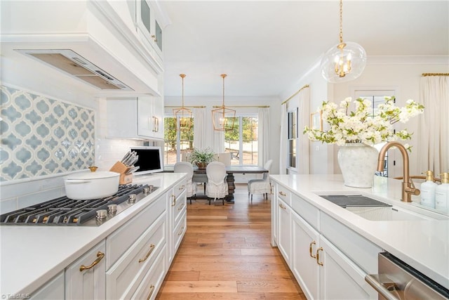 kitchen with premium range hood, a sink, ornamental molding, light countertops, and stainless steel appliances